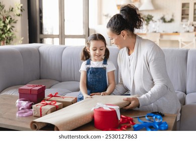 Little girl daughter helping her mom with wrapping packing in paper birthday Christmas New Year presents gift boxes at home together, preparing for celebration event - Powered by Shutterstock