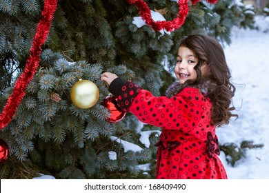 Little Girl In Decorating Christmas Tree Outside