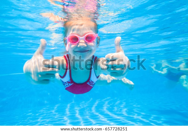 小さな女の子がプールで巧みに水中で泳ぐ の写真素材 今すぐ編集