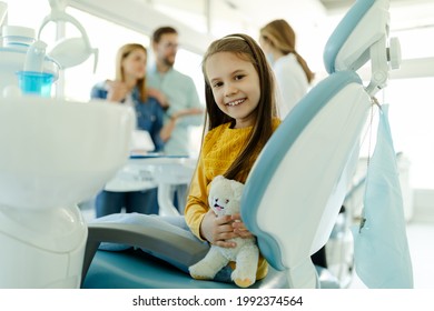 Little girl in dental office showing milk tooth while parent is discussing with dentist doctor. - Powered by Shutterstock