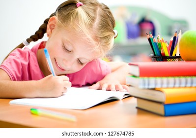 little girl at the desk is writing - Powered by Shutterstock