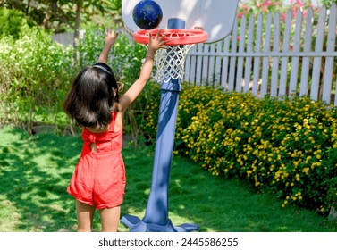 A  little girl with a determined expression dribbles a basketball on a sunny day in her backyard - Powered by Shutterstock