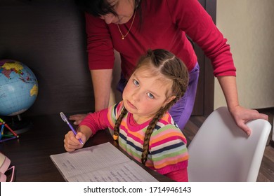 A Little Girl Doesn't Want To Learn Lessons. Sad Child Is Tired Of School Assignments. Mom Helps Her Daughter Do Her Homework. The Concept Of Home Education In Quarantine.