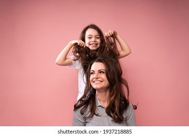 Little girl doing hairstyle to a woman with long dark hair pulling them up with her hands up - Powered by Shutterstock