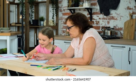 Little Girl Doing Homework with Grandmother in the Kitchen. Homeschooling and Educational Activity Concept