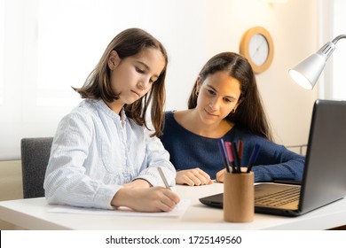 Little Girl Doing Homework With Her Older Sister At Home