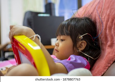 A Little Girl Is Doing A Neurofeedback Exam. Making EEG Electrodes.