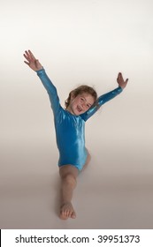 little girl doing the splits in blue leotard against studio white background