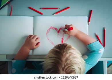 Little girl drawing red heart at white paper within red pens and pencils - Powered by Shutterstock