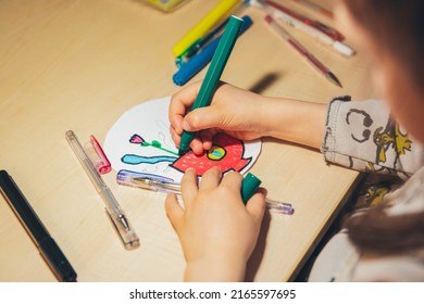 A little girl draws at home in the evening.