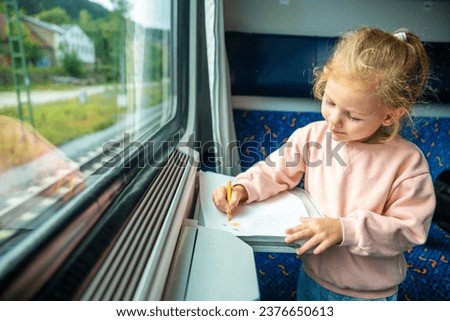 Little girl draws with pencils on white paper while traveling by railway in Czech republic, Europe. High quality photo