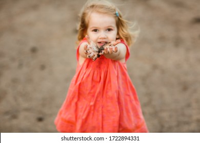 little girl in a dress smeared hands and goes in the dirty dirt road. earth after a rain. off-road. near a field with flowers poppies.