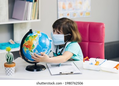 Little girl dressed in a doctor's suit treats the planet Earth. Little cute kid girl doctor puts a mask on the globe of the planet Earth. Save earth planet hands. Our future in your hands