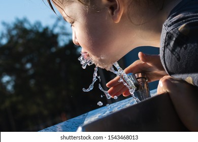 Little Girl Drink Water From Public Drinking Fountain
