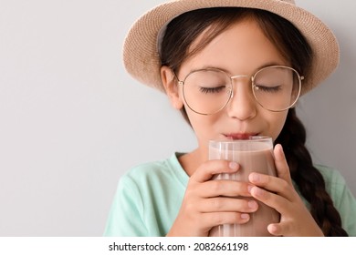 Little Girl Drinking Tasty Chocolate Milk On Light Background