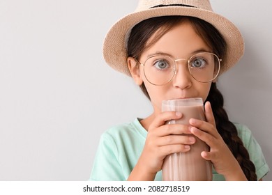 Little Girl Drinking Tasty Chocolate Milk On Light Background