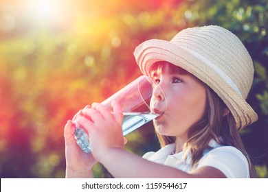 Little Girl Drinking Water Looking Side In A Summer Garden