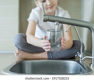 Little Girl Drinking From Water Tap Or Faucet In Kitchen. Pouring Fresh Drink. Healthy Lifestyle. Water Quality Check Concept. World Water Monitoring Day. Environmental  Pollution Problem