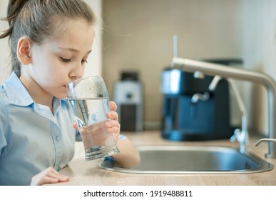 Little girl drinking from water tap or faucet in kitchen. Pouring fresh drink. Healthy lifestyle. Water quality check concept. World water monitoring day. Environmental  pollution problem