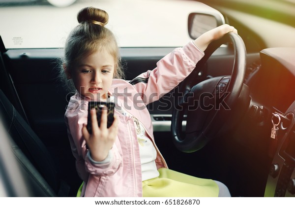 Little girl driver with a\
phone