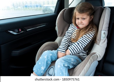 Little girl is driving in car. Kid child wants to go to toilet, pee and endures. Traveling, riding on road in safe baby seats with child belts. Fun family trip, activity with parents.