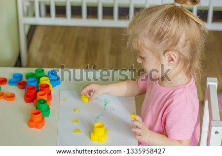 little girl drowing with paints prints and stamps colors.