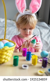 Little Girl In Easter Bunny Ears Painting Colored Eggs. Easter Family Holiday Celebration At Home And Craft Concept. Easter Eggs Crafts.