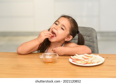 Little Girl Eating Apple With Honey. Symbol of the Jewish New Year Rosh haShana. - Powered by Shutterstock