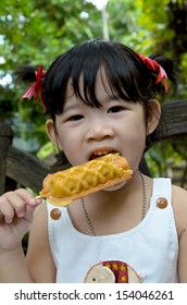 Little Girl Eating A Corn Dog.Kid Eating Corn Dog.