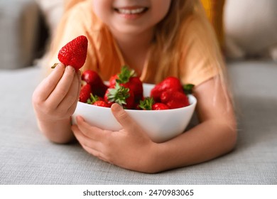 Little girl eating delicious strawberries in living room - Powered by Shutterstock