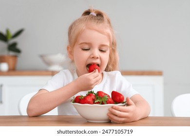 Little girl eating delicious strawberries in kitchen - Powered by Shutterstock