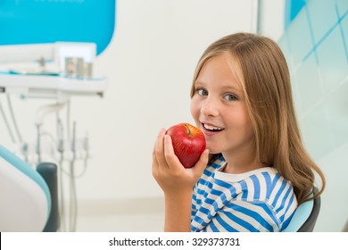 Little Girl Eating Fresh Apple In The Office Of Dentist