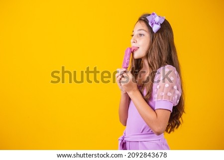 little girl eating a frozen popsicle. Adorable little girl with delicious ice cream against color background