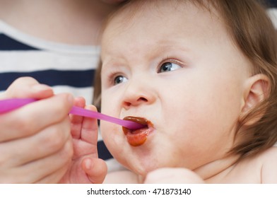 little girl is eating fruit puree , first solid foods