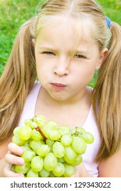 Little Girl Is Eating Grapes Outdoors