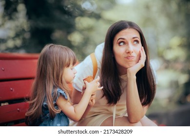 
Little Girl Eating Ice Cream Dessert Before Lunch Time. Stressed mom holding a sweet snack for her toddler child in the park 
