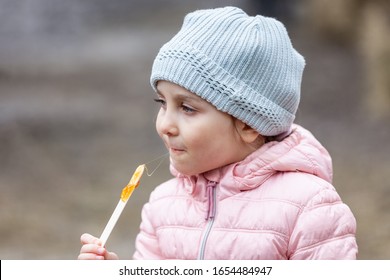 Little Girl Eating Traditional Maple Syrup Taffy Candy At Outdoor Public Spring Festival In Quebec, Canada. Selective Focus On Face.