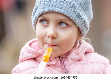 Little Girl Eating Traditional Maple Syrup Taffy Candy At Outdoor Public Spring Festival In Quebec, Canada. Selective Focus On Face.