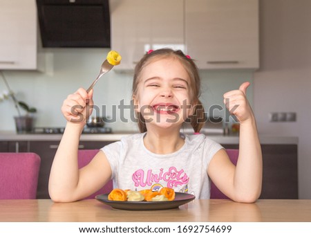 Little girl eats colorful dumplings. Coronavirus quarantine concept. Stay at home.