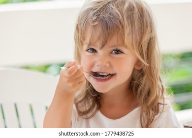 kleines Mädchen isst Honig mit Löffel