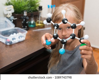 A little girl in elementary school constructs a model of a molecule and conducts simple chemical experiments. A microscope, test tubes, a metal robot are on a table. STEM education. AI.  - Powered by Shutterstock