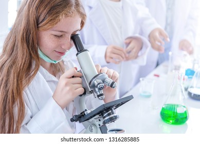 Little Girl At An Elementary School, Using Microscope Research, Testing In Science Class. Toddler Girl Doing Biochemistry Research In Lab. Child Have Experiment With Test Tubes In Bright Modern Lab.