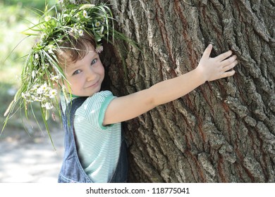 The little girl embraces a big tree