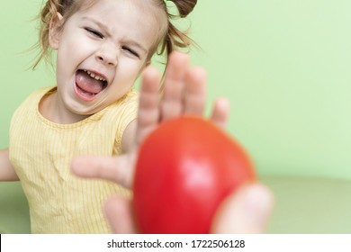 A Little Girl Emotionally Refuses The Proposed Tomato. Children Do Not Like Vegetables, Unbalanced Nutrition Of Preschoolers