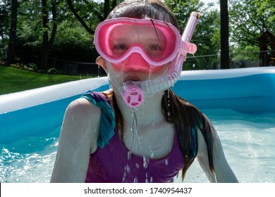 A Little Girl Enjoys Sunny Summer Fun, Swimming In A Backyard Kiddie Pool.