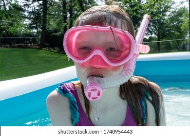 A Little Girl Enjoys Sunny Summer Fun, Swimming In A Backyard Kiddie Pool.