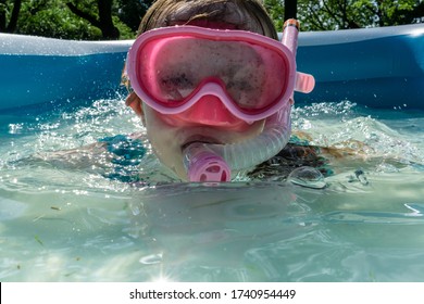 A Little Girl Enjoys Sunny Summer Fun, Swimming In A Backyard Kiddie Pool.