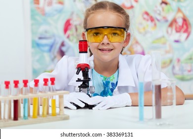 Little Girl Experimenting In Elementary Science Class - With Protective Gloves And Glasses