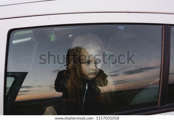 Little girl
face behind the window with
reflections