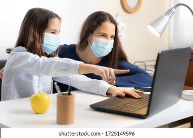 Little Girl With Face Mask Doing Homework With Her Older Sister At Home With Laptop